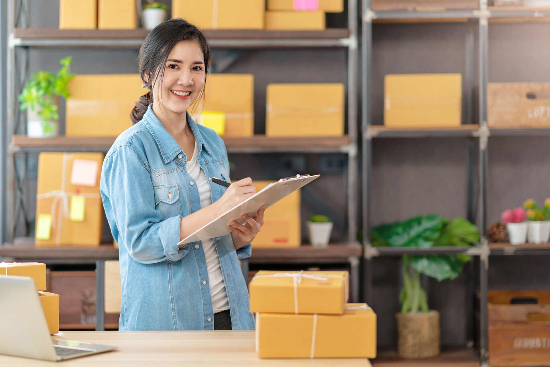 A woman in a fulfillment center is checking off a list of shipments.