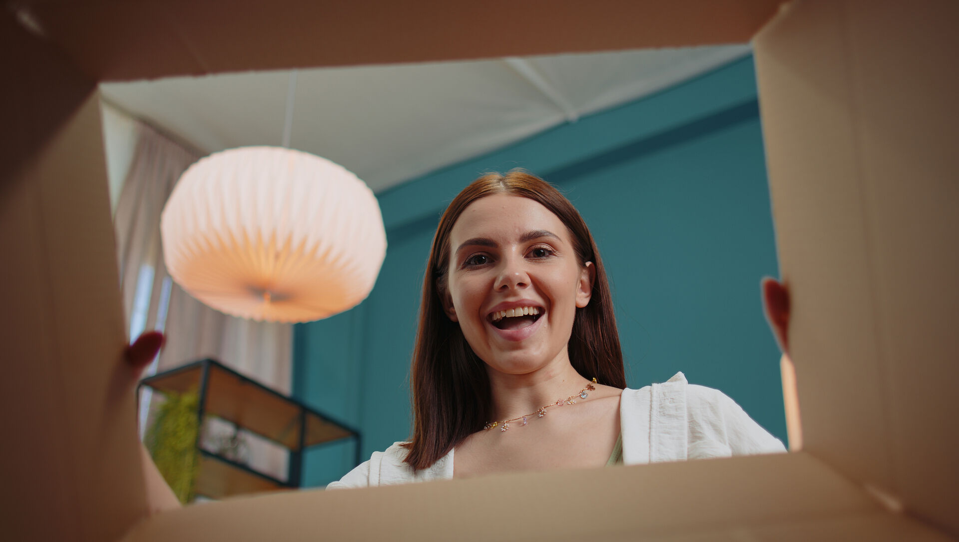 A woman looks happily into an opened box.