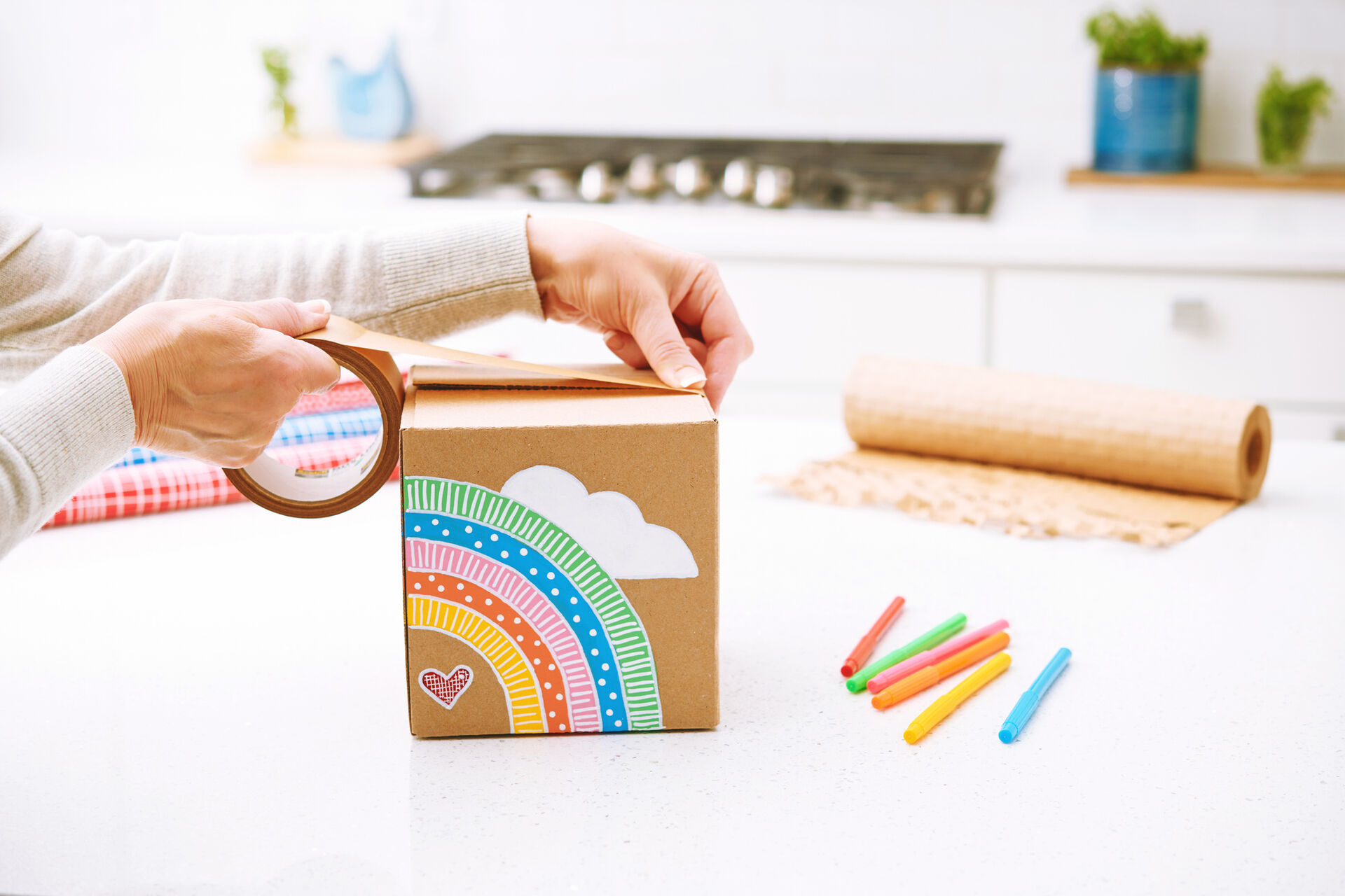 A woman is packing a parcel with a brightly printed cardboard box.