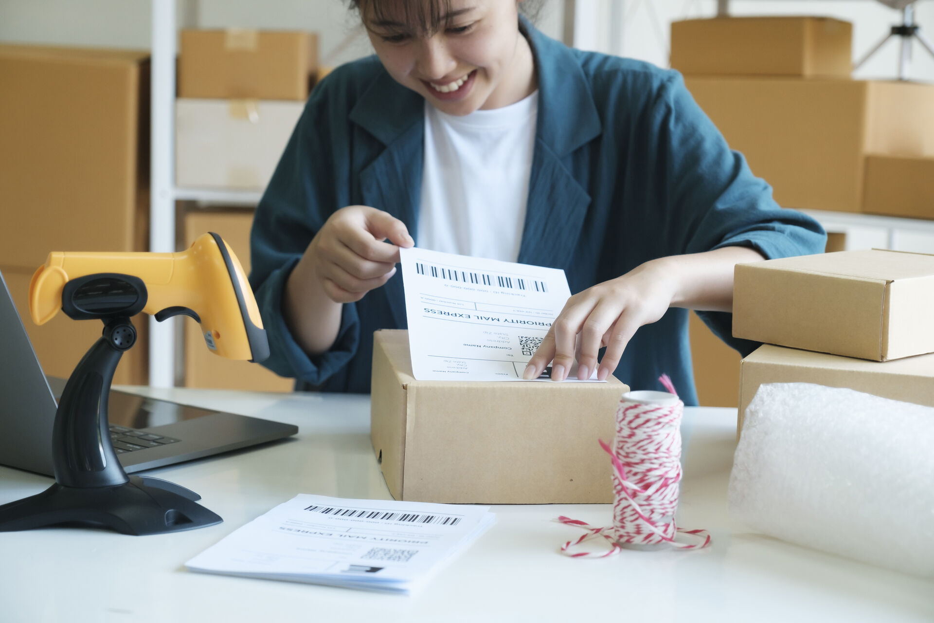 Eine junge Frau klebt ein Versandetikett auf ein Paket