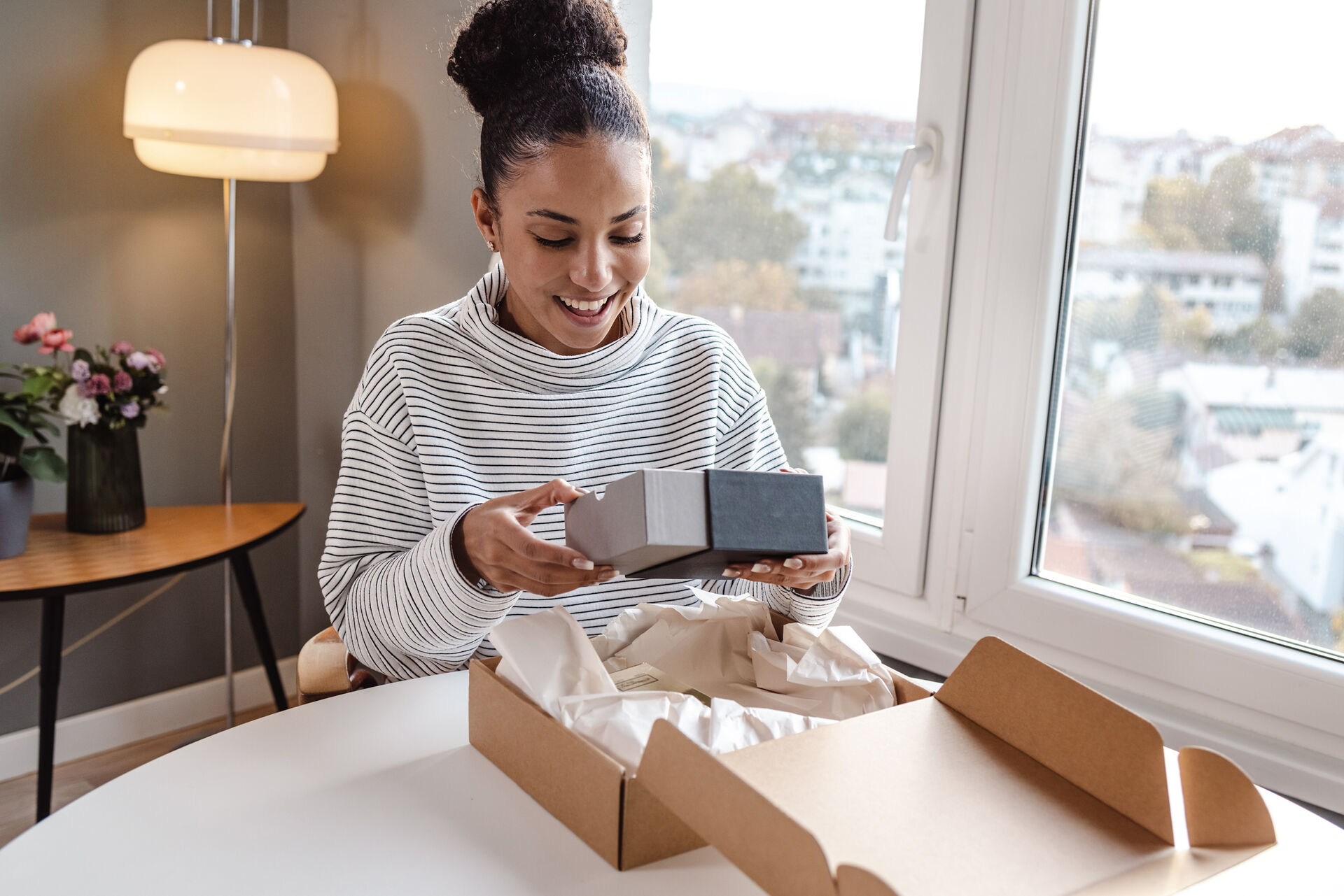 A woman joyfully unpacks a package.