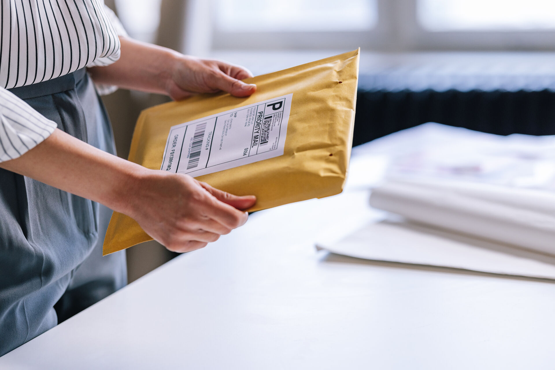 Eine Frau hält ein Paket mit ausgedrucktem Versandlabel in den Händen.